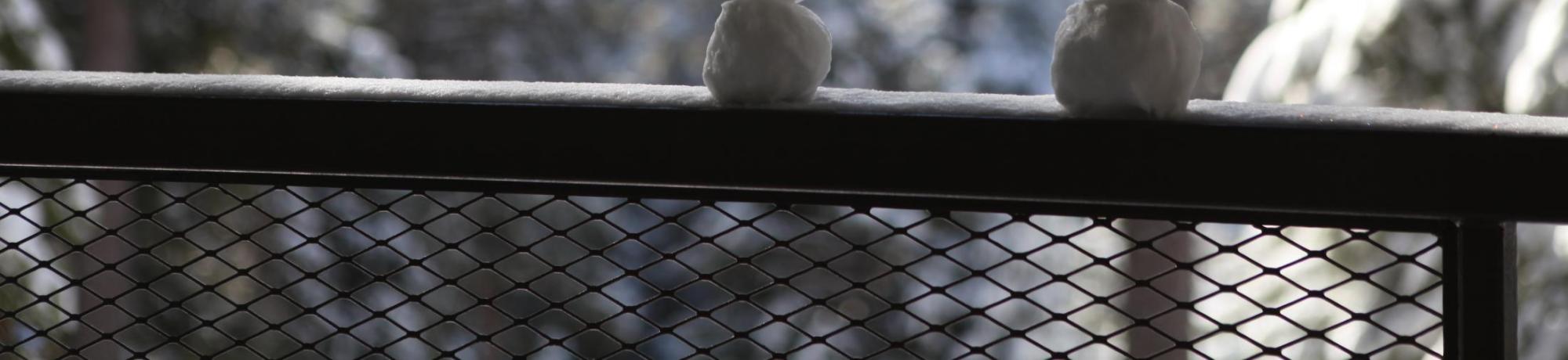 Two snowmen sitting on a deck